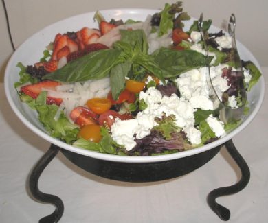 A bowl of salad with feta cheese and strawberries.