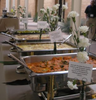 A buffet of food with flowers on the table.