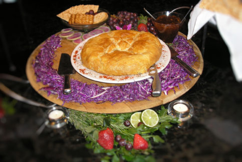 A pie on a plate with some fruit and other food