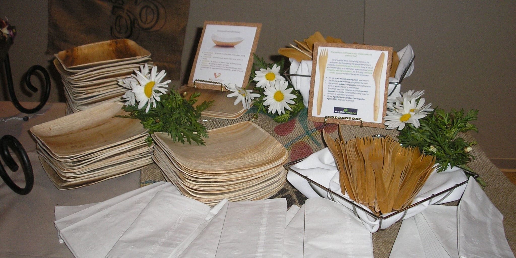 ecoplateware A table with plates, napkins and flowers on it.