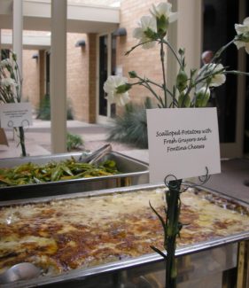 A buffet of food with flowers on the table.