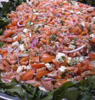 A large salad with tomatoes, onions and feta cheese.