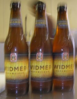 Three bottles of beer are sitting on a counter.