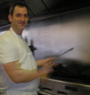 A man holding a spatula in front of an oven.