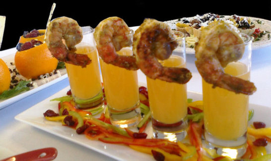 A tray of shrimp cocktails with orange juice.