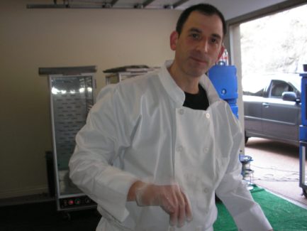 A man in white lab coat standing next to a refrigerator.