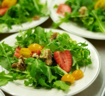 A plate of salad with strawberries and nuts.